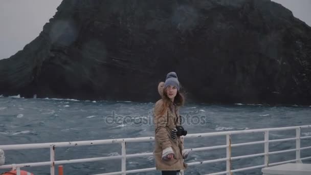 Young beautiful woman with camera standing on the board of the ship and looking around. Tourist on the speed motorboat. — Stock Video