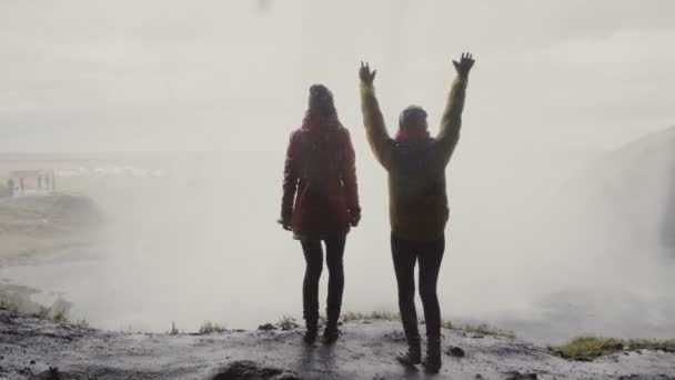 Vue arrière de deux touristes heureuses près de la cascade de Gljufrabui en Islande. Les femmes sautent de joie près de la vue . — Video