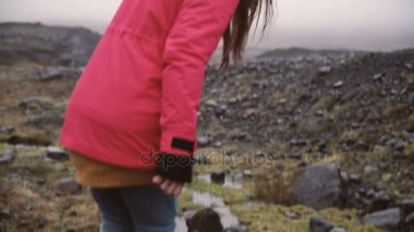 Arkadan Görünüm genç kadının kayalık tepede hiking. Kadın bataklıkları yürüyüş İzlanda'nın tek başına keşfetmek seyahat.