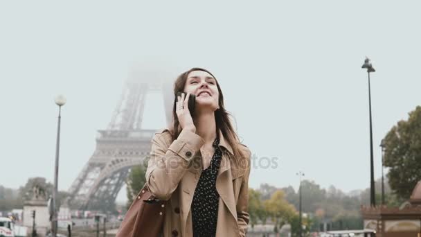 Mujer joven y elegante caminando cerca de la torre Eiffel en París, Francia y hablando por teléfono móvil con amigos . — Vídeos de Stock