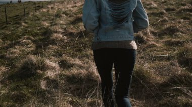 Arkadan Görünüm alanını Nehri yakınında yürürken genç şık kadın. Kadın'İzlanda at çiftliği.