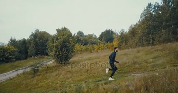 Corredor yendo cuesta arriba en un camino a través del país. Vista lateral del dron. Atleta deportista concentrado logrando objetivo de vida . — Vídeo de stock