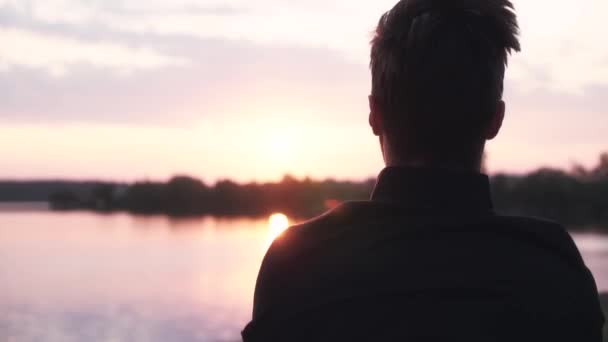 Treinamento de homens em câmara lenta perto do pôr-do-sol. Voltar vista desportista masculino aquecendo na água tranquila e panorama da floresta . — Vídeo de Stock