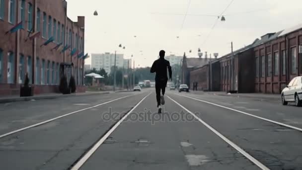2 in 1. Mann läuft schnell in einer alten Stadtstraße. Echtzeit. Freiheitsbegriff. Kamera rückt jungen Sportler auf die Pelle. — Stockvideo