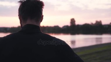 Ağır çekim özgür bir adam güneş doğarken meditasyon. Düşünceli erkek zevk huzurlu sabah su panorama görünümünü geri.