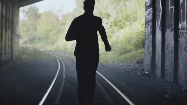 Slow motion man silhouet uitgevoerd op treinrails. Achteraanzicht. Abstracte achtergrond schot eindigt. In de uitoefening van de vrijheid. — Stockvideo