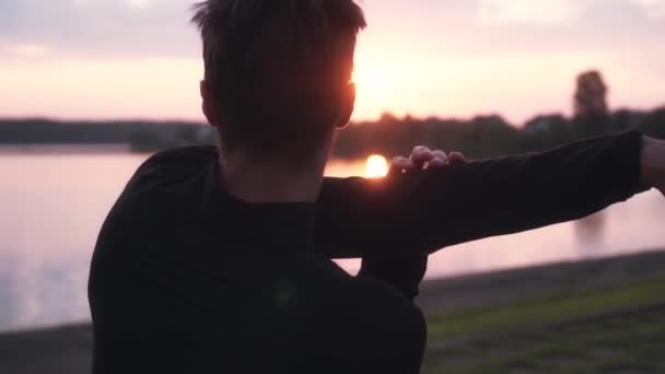 Slow motion free man exercising sunrise lake. Back view of male swinging arms at beautiful morning water panorama. — Stock Video