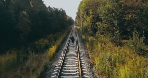 Muž běží na podzimní lesní železnice. Zadní pohled na DRONY. Atlet na cestě k jasné vize horizont. Filmový záběr. — Stock video