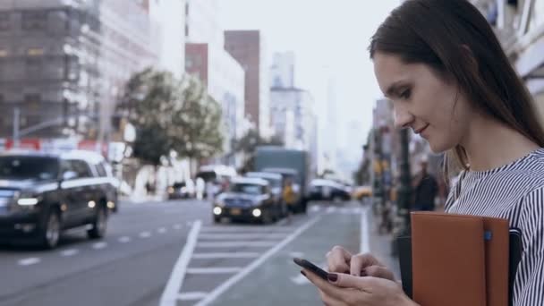 Glad vacker kvinna står i centrum av New York, Amerika och med smartphone, att skriva meddelanden. — Stockvideo