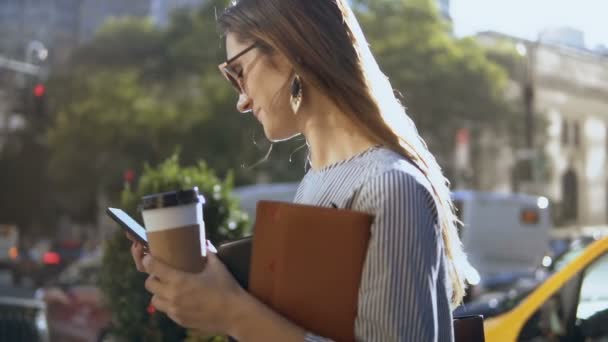 Joven mujer de negocios feliz con café y documentos utilizando smartphone en el centro en un día soleado. Movimiento lento . — Vídeos de Stock