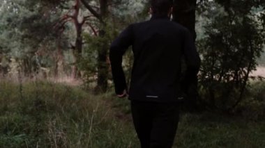 Ağır çekim. Derin orman keşfetmek koşan adam. Kamera ülke runner huzurlu sonbahar sahne zevk izler.