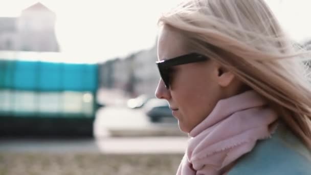Portrait de confiant fille blonde caucasienne 20s. Mouvement lent calme souriant jeune femme marchant dans des lunettes de soleil élégantes . — Video