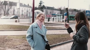 İki beyaz arkadaş birbirlerine fotoğraf çekmek. Güzel kızlar birlikte takılmak, smartphone fotoğraf çekmek. Ağır çekim.