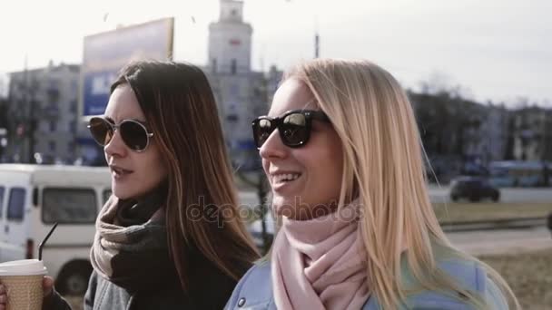 Zeitlupe. Zwei kaukasische Frauen unterhalten sich. Zwanzigjährige in stylischer Kleidung und Sonnenbrille plaudern lächelnd auf der Straße. — Stockvideo