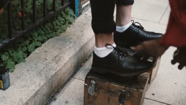 Närbild av manliga, affärsman fötter på ett stativ. Sko shiner arbetar på gatan, polering de svarta skorna. — Stockvideo