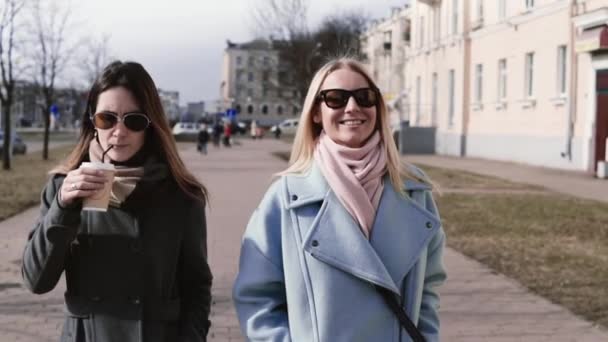 Slow motion. Unga kaukasiska flickor gå tillsammans. 30s kvinnliga vänner konversation med kaffe. Glada kvinnor talar. — Stockvideo