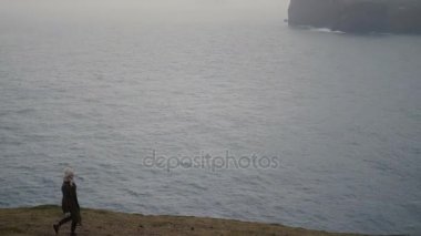 Sisli gün denizin kıyısında yürüyen genç sarışın kadın. Çekici Bayan yalnız dağlarda hiking.