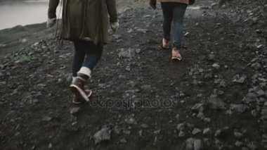 Arkadan görünüşü buz gölünde yürüyen genç bir çift. Erkek ve kadın birlikte İzlanda'daki dağlarda hiking.
