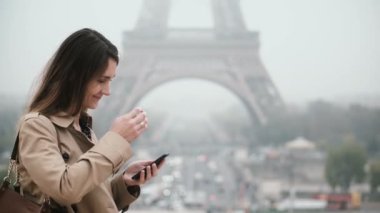 Fransa'nın Paris, Eyfel Kulesi yakınındaki şehir merkezinde duran ve smartphone kullanarak genç şık kadın portresi.