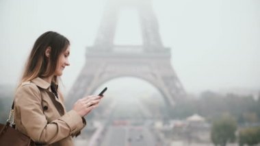 Hareket eden telefon içinde sisli sabah genç güzel kadın. Fransa'nın Paris, Eyfel Kulesi yakınındaki Smartphone kullanarak erkek