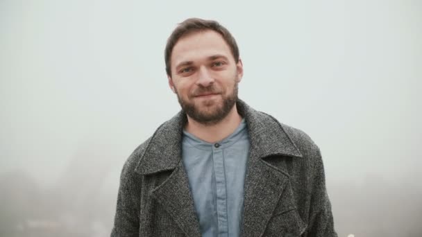 Retrato de un joven guapo con barba de pie sobre el fondo de la torre Eiffel y mirando a la cámara . — Vídeo de stock