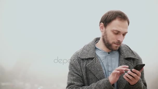 Ομίχλη το πρωί στο Παρίσι, Γαλλία. Όμορφος άνδρας χρησιμοποιώντας το έξυπνο κινητό τηλέφωνο με οθόνη αφής κοντά στον Πύργο του Άιφελ. — Αρχείο Βίντεο