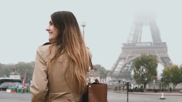 Joven hermosa mujer caminando en la mañana brumosa cerca de la torre Eiffel en París, Francia y hablando por teléfono móvil . — Vídeo de stock