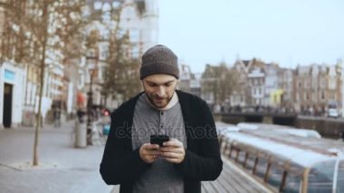 4 k Beyaz turist adam Smartphone ile yürüyor. Casual yakışıklı sokağın ortasında gülümseyen yetişkin erkek manifatura sakallı.