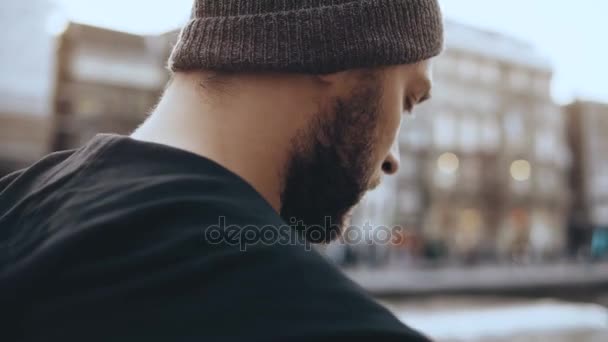 4K Viajero caminando con smartphone en Amsterdam. Muy de cerca. Hombre en sombrero camina a lo largo del antiguo terraplén del río de la ciudad . — Vídeos de Stock