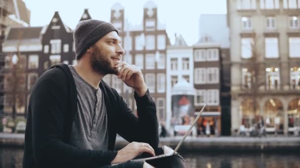 4K European adult man sitting with laptop outside. Popular online blogger working outdoors. Side view lifestyle shot. — Stock Video