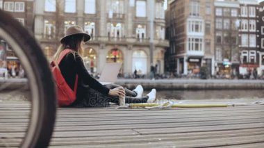 4 k genç yaratıcı kız ile laptop dışında oturuyor. Moda sanat blogger açık havada çalışır. Özgürlük. Steadicam yaşam tarzı atış.