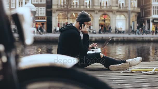 4 k Europejskiej biznesmen pracy na zewnątrz. Mężczyzna rozmawia przez telefon, siedząca z laptopem. Rzeki łodzi i tramwajem przechodząc przez. — Wideo stockowe