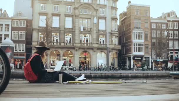 4 k Student meisje werkt met laptop in de straat. De werknemer van de kunst van mode met rode rugzak en thermische mok. Levensstijl schot. — Stockvideo