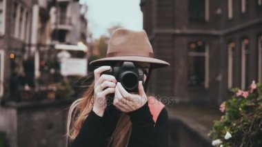 Bir kamera ile mutlu beyaz bir kadın portresi. Resim 4 k ön görünüm alarak şık şapka çekici neşeli Bayan.