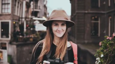 Yaşam tarzı portre. 4k profesyonel fotoğrafçı. Çekici neşeli Bayan ile bir fotoğraf makinesi şık şapkalı bir fotoğraf çeker.