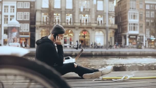 Pengusaha Kaukasia 4K dengan laptop di luar. Pria yang berbicara di telepon duduk di jalan, Amsterdam. Pengusaha . — Stok Video