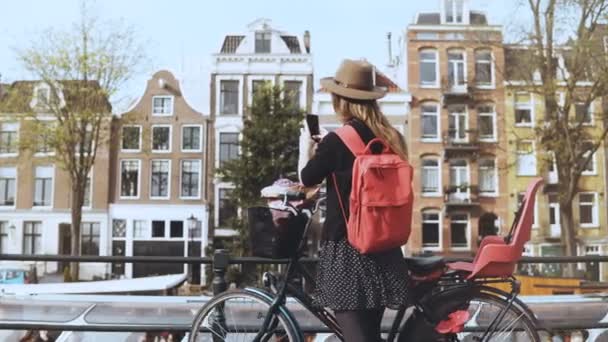 Turist damen med cykel tar foton på bron. Söt kaukasiska kvinna fotografier magnifika gamla stan arkitektur 4k — Stockvideo
