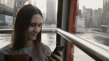 4 k iş kadını hava füniküler kabinde yazarak. New York, Manhattan. Çekici Bayan smartphone içinde ada tramvay ile.