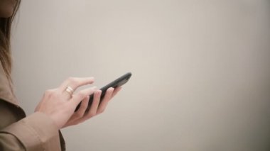 Yakın çekim yazarak ekranda eller görünümünü. Belgili tanımlık smartphone touchscreen ile sisli günde kullanan genç kadın.