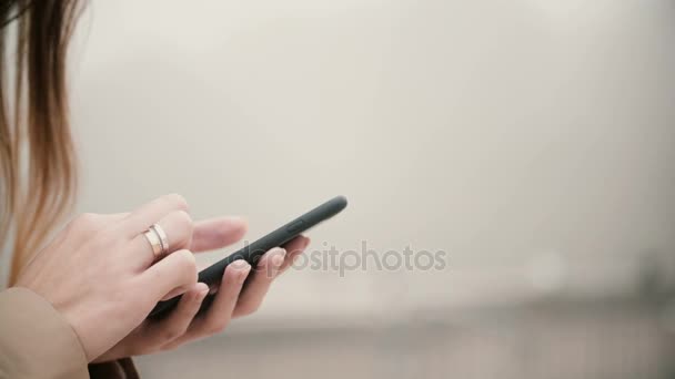 Vista de cerca de las manos femeninas que sostienen el teléfono móvil con pantalla táctil. Mujer usando smartphone en el parque de niebla . — Vídeo de stock