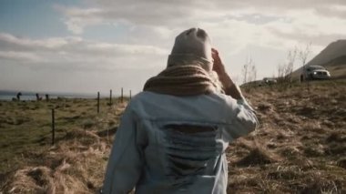 Doğa dışarıda şehrin içinden atlar farm yakınındaki alan üzerinde yürüyen genç şık kadın arkadan görünüm.