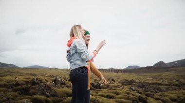 İzlanda'daki lav sahada ayakta ve bir şey üzerinde parmak ile işaret eden iki turist kadın. Mutlu kadın söz.