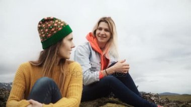 Lav sahada oturan iki mutlu kadın konuşmak ve İzlanda yosun kaplı. Turistler arkadaş yürüyüş sonra dinlenme.