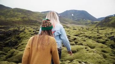 İzlanda lav alanına yürürken iki turist kadın yosun kaplı. Kızlar yükseltir eller, mutlu hissediyor ve özgürlük.