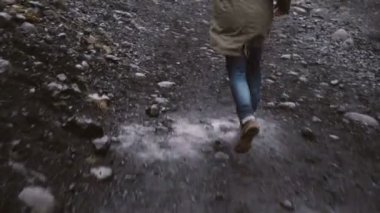 Biri uzak İzlanda'kayalık yol aracılığıyla çalışan Çizmeli endişeli erkek ayak görünümünü yakın çekim.