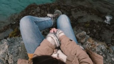 Yakın çekim görünümünü Rock mavi su yakınında oturan bir genç bayan. Kadın yalnız hiking sonra dinlenme seyahat.