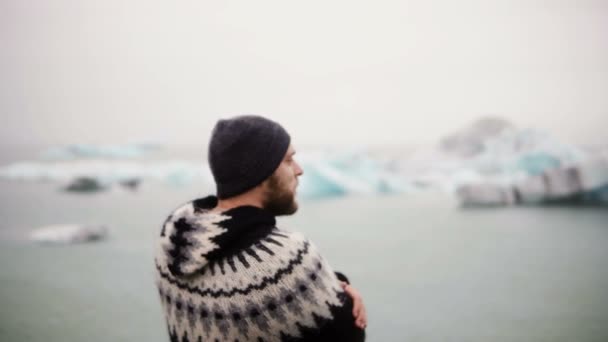 Νέοι γενειοφόρος άνδρας στέκεται στη λιμνοθάλασσα Jokulsalon πάγο και να ψάχνει παγετώνες, Βόρεια φύσης στην Ισλανδία. — Αρχείο Βίντεο