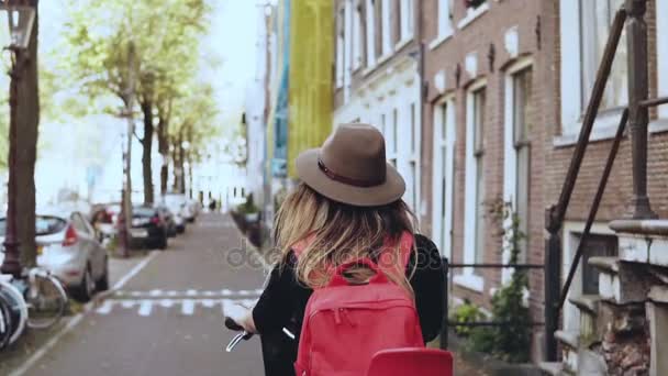 Flicka på en cykel med en röd baksätet. Slow motion närbild. Glad kvinnlig turist. Leisure cykeltur längs gatan. — Stockvideo