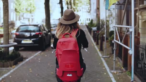 Vista trasera. Mujer con mochila roja en bicicleta. En cámara lenta. Emocionada turista caucásica. Blogger de belleza de estilo de vida . — Vídeos de Stock