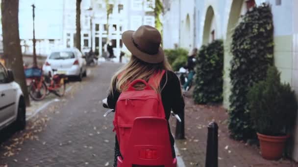 Vista traseira. Estudante menina caucasiana monta uma bicicleta. Movimento lento. Feliz viajante diário local. Estilo de vida plano de fundo . — Vídeo de Stock